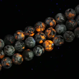 Detailed view of natural Yooperlite round beads showing vibrant orange fluorescence