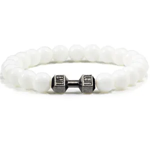 Detail van een wit kralen yoga armband met een leuk metalen dumbbell bedeltje voor fitness.