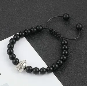 Detailopname van de zwarte lavasteen kralenarmband met zilveren helm bedel en koord.