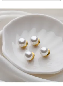 Pearl anti-glare button detail shot, white round pearl with gold base in ceramic dish.