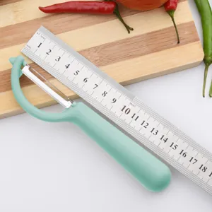 Stainless steel fruit peeler with ergonomic green handle, kitchen tool for peeling potatoes.