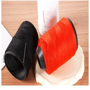Detailed view of large polyester sewing thread spools in three colors with needles.