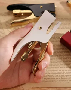 Vue detaillee d'agrafeuse vintage portable, outil de bureau blanc et dore elegante.