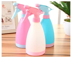 Detail view of multi-color plastic spray bottles set placed on desktop for home garden watering.