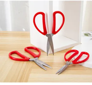 Stainless steel scissors detail view featuring red plastic handle and sharp blades for office use.