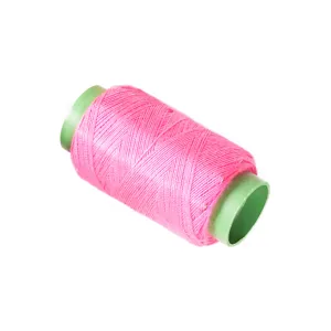 Bright pink sewing thread spool on white background for DIY craft and garment repair.