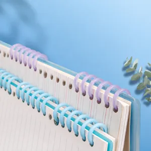 Detailed close-up of colorful plastic loose-leaf binder rings and punched paper for notebooks.