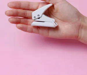 Close-up detail of a compact white single-hole paper puncher held in hand for scale.