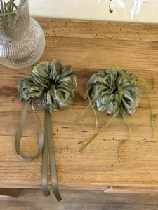 Gedetailleerde weergave van twee groene organza scrunchies met linten op houten tafel