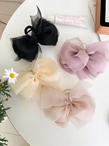 Gedetailleerd overzicht van vier kleuren grote haarklemmen met een strik van gaas