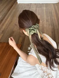Elegante groene scrunchie met lint en strik, detailweergave op een dameskapsel.