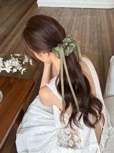 Elegante achteraanzicht van een vrouw met een groene organza scrunchie met lange zijden linten