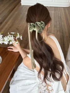 Elegante groene organza scrunchie met lint, gedragen op lang golvend bruin haar.