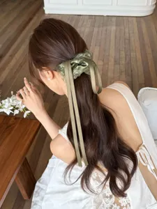 Elegante groene scrunchie met lint voor lang bruin golvend haar, achteraanzicht getoond