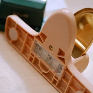 Compact 4mm hole puncher with durable plastic structure and clear chip tray for stationery use.