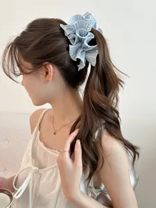 Detailed view of light blue ruffled satin banana clip with pearl accents on ponytail