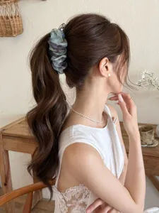 Gros plan d'une barrette banane à fleurs élégante sur une queue-de-cheval ondulée brune.