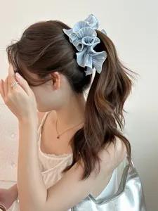 Close-up detail of a blue pleated ruffle banana clip with pearls in a ponytail.