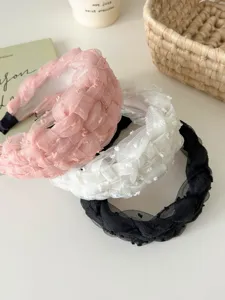 Detalle de tres diademas trenzadas de malla en rosa, blanco y negro estilo coreano elegante
