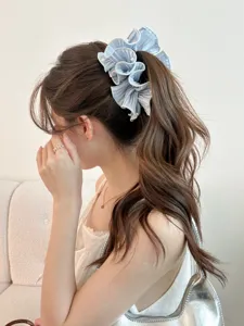 Detail showing a light blue ruffled satin banana hair clip with elegant pearls.