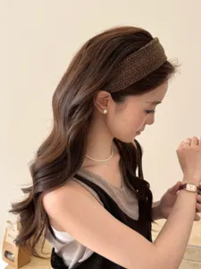 Detail view of a brown knitted wide headband worn by a model for a high top hairstyle