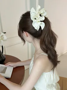 Elegant pleated ruffled satin hair clip with pearls shown on a woman's ponytail