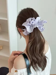 Detail view of a lavender pleated satin banana hair clip with pearls worn by a model