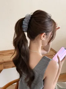 Pince à cheveux banane bouffante en maille bleu gris sur un détail de queue de cheval