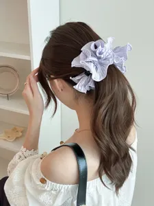 Detailed view of a lavender ruffled satin banana clip with pearls on a wavy ponytail