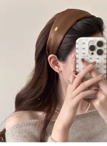 Detail of a brown silk-finish wide headband with a small gold metal label