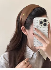 Detailed view of an elegant brown satin wide headband with a small gold label tag