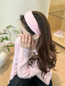 Asian woman wearing a stylish pink knitted wide-brimmed headband in a cozy indoor setting