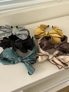 Detail view of six elegant bow headbands in various colors with contrasting piped edges