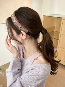 Elegantes Strickstirnband mit glitzernden Strasssteinen und Perlen am Modell gezeigt
