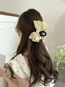 Dettaglio ravvicinato di una pinza per capelli con fiocco a righe gialle e bianche