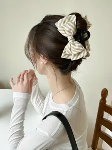 Dettaglio di un mollettone per capelli a fiocco a righe in uno chignon elegante