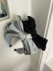 Close-up of oversized bow headbands in light blue and black with contrast piping