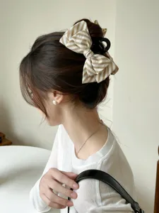 Dettaglio di una molletta per capelli con fiocco a righe indossata in uno chignon