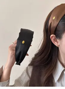 Detail of silk-like wide headbands in black and brown with elegant gold logo tags.