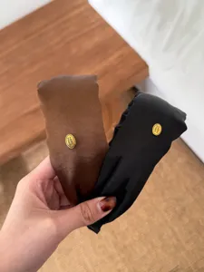 Close-up of elegant satin-finish headbands in brown and black with gold label details.