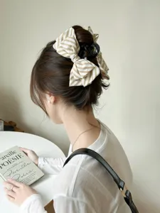 Dettaglio elegante molletta per capelli a fiocco a righe beige su acconciatura raccolta