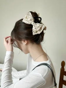 Primo piano di un'elegante molletta per capelli con fiocco a righe su uno chignon basso