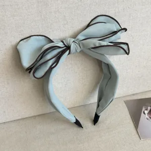 Elegant mint blue oversized bow headband with brown contrast piping for a classic chic look