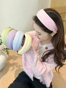 Close-up of pastel knit wide headbands in various soft cream colors held by a young model