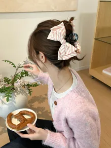 Vista dettagliata di un fermaglio per capelli con fiocco a righe rosa e bianco su un raccolto.