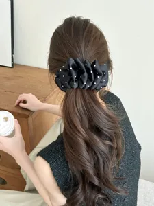 Rear view showing a stylish black polka dot bubble banana clip worn in long wavy hair