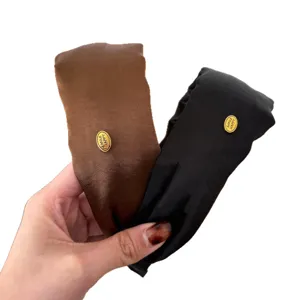 Pair of French style glossy headbands in brown and black with gold 'SMILE HAPPY' label