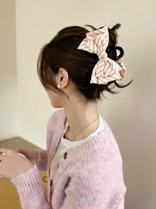 Vista dettagliata di una pinza per capelli con fiocco a righe rosa e bianche in uno chignon