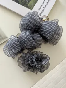 Nahaufnahme von drei eleganten Haarklammern mit schwarz-weißem Gingham-Blumenmuster