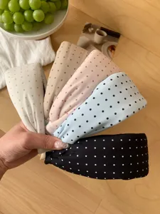 A collection of colorful polka dot wide headbands held by hand for a lifestyle view